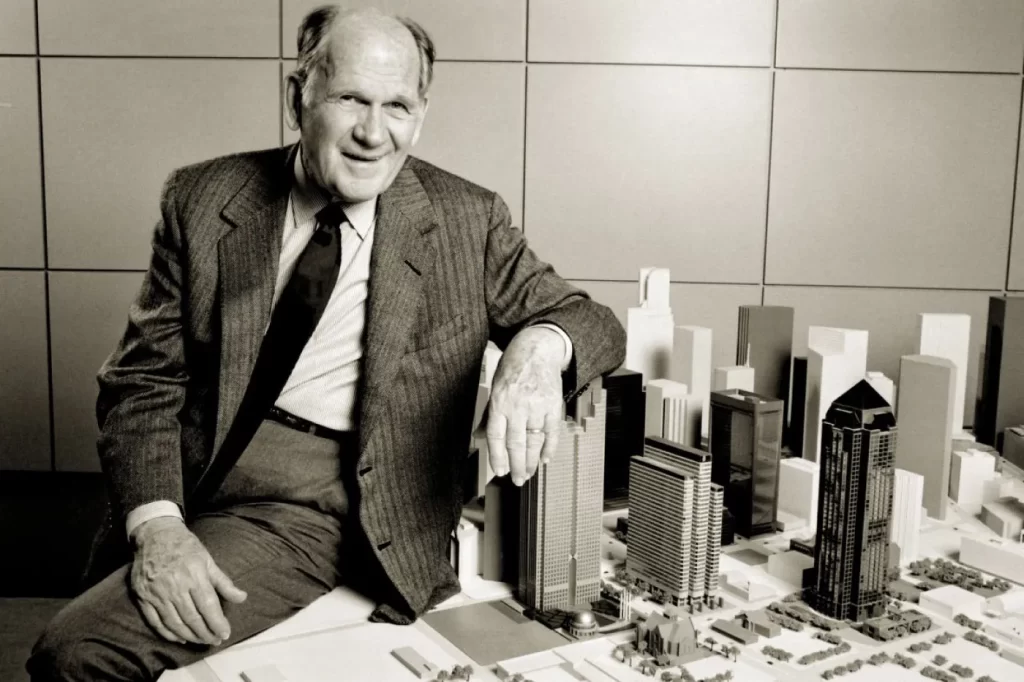 Fred Trammell Crow (father of Harlan Crow) sitting on a desk next to a miniature architectural model of a city